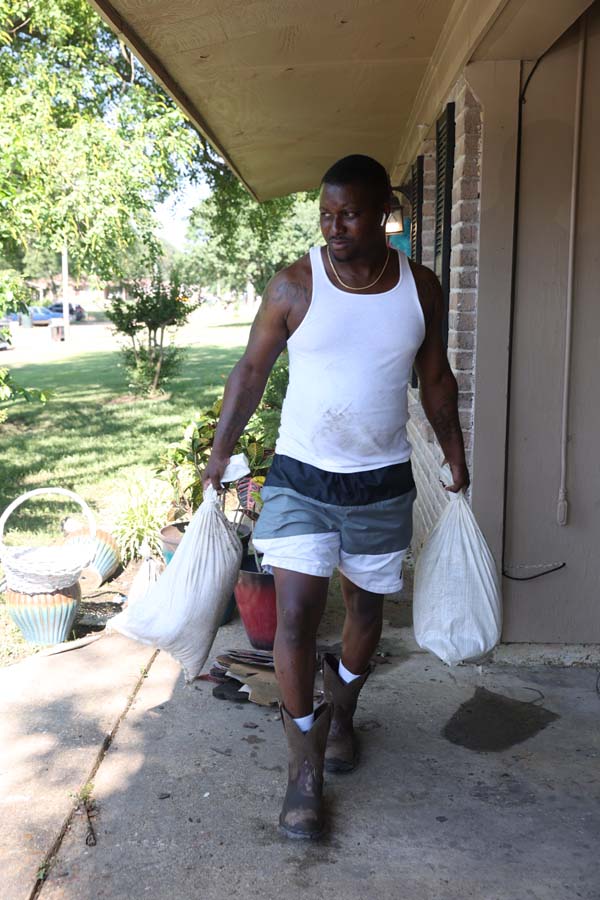 Desmond Jones removes sandbags that were placed in front of his mother’s house on Murphree Drive, in the Glendale subdivision.