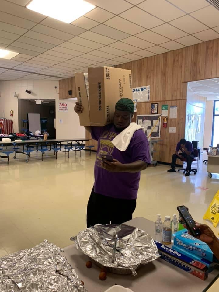 Troy Brown Jr., a teacher at Greenwood High School, lifts a box of food at East Elementary.