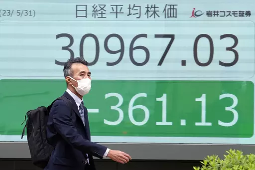 A person walks past an electronic stock board showing Japan's Nikkei 225 index at a securities firm Wednesday, May 31, 2023, in Tokyo. Asian stock markets sank Wednesday ahead of a vote by Congress on a deal to avert a government debt default, while a downturn in Chinese factory activity deepened, adding to signs global economic activity is weakening.(AP Photo/Eugene Hoshiko)