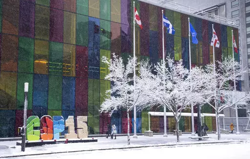 Delegates arrive at the convention centre at the COP15 UN conference on biodiversity during a snowfall in Montreal, Friday, Dec. 16, 2022. (Paul Chiasson /The Canadian Press via AP)
