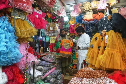 A Pakistani browses children's clothes at a market as he shops for the upcoming Eid al-Fitr celebrations, which marks the end of the Islamic holy month of Ramadan, in Peshawar, Pakistan, Wednesday, March 26, 2025. (AP Photo/Muhammad Sajjad)