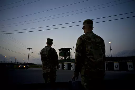 In this June 5, 2018 photo, reviewed by U.S. military officials, troops stand guard outside Camp Delta at the Guantanamo Bay detention center, in Cuba. The 20th anniversary of the first prisoners' arrival at the Guantanamo Bay detention center is on Tuesday, Jan. 11, 2022. There are now 39 prisoners left. At its peak, in 2003, the detention center held nearly 680 prisoners. (AP Photo/Ramon Espinosa, File)