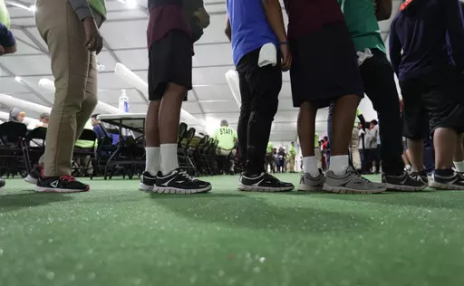 In this July 9, 2019, file photo, immigrants line up in the dinning hall at the U.S. government's newest holding center for migrant children in Carrizo Springs, Texas. The Biden administration plans to partially end the 27-year-old court supervision of how the federal government cares for child migrants, shortly after producing its own list of safeguards against mistreatment. (AP Photo/Eric Gay, File)