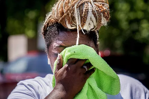 Nicole Brown wipes sweat from her face while setting up her beverage stand near the National Mall on July 22, 2022, in Washington. What's considered officially “dangerous heat” in coming decades will likely hit much of the world at least three times more often as climate change worsens, according to a new study. (AP Photo/Nathan Howard, File)