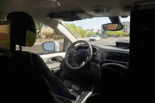 A Waymo minivan moves along a city street as an empty driver's seat and a moving steering wheel drive passengers during an autonomous vehicle ride, on April 7, 2021, in Chandler, Ariz. The U.S. government's highway safety agency has opened another investigation of automated driving systems, this time into crashes involving Waymo's self-driving vehicles. The National Highway Traffic Safety Administration posted documents detailing the probe on its website early Tuesday after getting 22 reports of