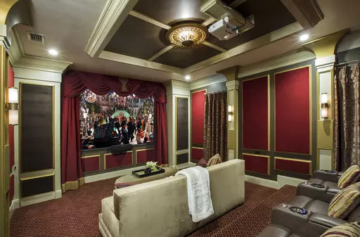 This image provided by John McClain Design shows a home theater with red velvet on the wall panels. The 'champagne-hued velvet' is on the big couch in foreground. For an Orlando, FL project, designer John McClain and his client wanted to evoke an Art Deco aesthetic, yet still design a functional state-of-the-art home theater. "We upholstered portions of the walls with red velvet inside of wooden accent panels to gain the hard-to-soft-surface-ratio that would normally be accomplished with acousti