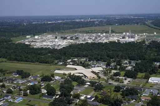 The Fifth Ward Elementary School and residential neighborhoods sit near the Denka Performance Elastomer Plant, back, in Reserve, La., Sept. 23, 2022. The EPA sued Denka Performance Elastomer LLC, arguing that its petrochemical operations in southern Louisiana posed an unacceptable cancer risk to the mostly-Black community nearby. The EPA has demanded that the company reduce toxic emissions from its plant that makes synthetic rubber. (AP Photo/Gerald Herbert, File)