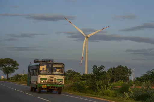 A bus drives past a windmill farm in Anantapur district, Andhra Pradesh, India, Sept 14, 2022. The key priority for India at the upcoming U.N. climate conference will be how to pay for the transition away from fossil fuels for energy and industries to meet temperature limit targets, according to a senior official who'll be part of the negotiations. (AP Photo/Rafiq Maqbool)