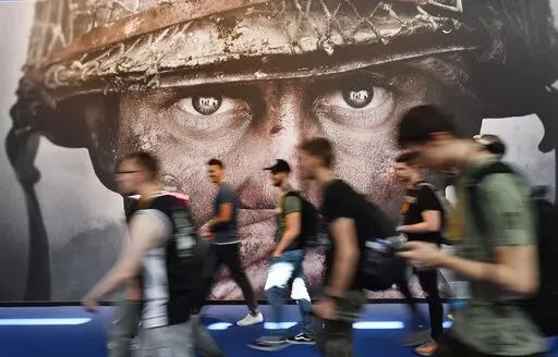 Visitors passing an advertisement for the video game 'Call of Duty' at the Gamescom fair for computer games in Cologne, Germany, Tuesday, Aug. 22, 2017. Microsoft says it struck a deal to make the hit video game Call of Duty available on Nintendo for 10 years when its $69 billion purchase of game maker Activision Blizzard goes through. The announcement Wednesday, Dec. 7, 2022 is an apparent attempt to fend off objections from rival Sony. (AP Photo/Martin Meissner, File)