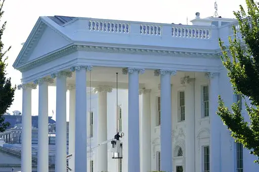 A worker works on the light fixture over the North Portico of the White House in Washington, Friday, Sept. 3, 2021. (AP Photo/Susan Walsh)