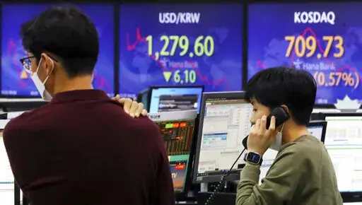 A currency trader talks on the phone near a screen showing the foreign exchange rate between U.S. dollar and South Korean won, center, at a foreign exchange dealing room in Seoul, South Korea, Thursday, Dec. 22, 2022. Shares advanced in Asia on Thursday after a rally on Wall Street as investors welcomed a report showing U.S. consumer confidence is holding up despite the Federal Reserve’s campaign to fight inflation by raising interest rates. (Choi Jin-suk/Newsis via AP)