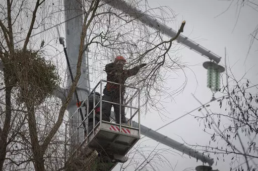 Workers of the electricity supply company DTEK maintain power lines by cutting off excess branches in Kyiv, Ukraine, Thursday, Dec. 8, 2022. Ukrainian utility crews struggling to patch up power lines during a two-month Russian military blitz targeting Ukrainian infrastructure are learning to adapt. And just as on the battlefield, Ukrainians are learning to respond quickly on the new energy front drawn inside homes, hospitals, offices, and schools in yet another act of defiance against a powerful