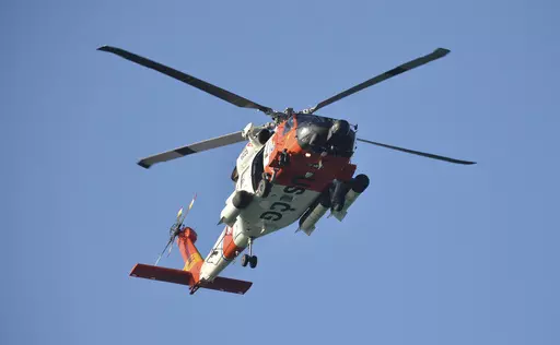 A U.S. Coast Guard helicopter flies over the Venice Fishing Pier Thursday morning, April 6, 2023, as emergency crews search a debris field in the Gulf of Mexico after a small airplane crash Wednesday night. Police say the bodies of two men and two women have been recovered following a small plane crash just off Florida's Gulf Coast. (Mike Lang/Sarasota Herald-Tribune via AP)