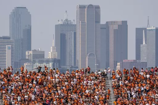 The Dallas skyline rises behind the Cotton Bowl stands as Texas fans watch during the first half of an NCAA college football game against Oklahoma at the Cotton Bowl, Saturday, Oct. 8, 2022, in Dallas. U.S. metropolitan areas increased their populations by almost half a percent last year in another sign that flight from urban areas during the first year of the pandemic either slowed down or reversed in its second year as people moved to Sunbelt metros in Texas and Florida by the tens of thousand