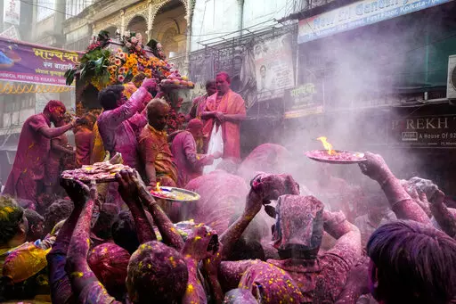 Hindu devotees with offerings make way to reach the car which carried the deity Shri Krishna during the Holi festival in Kolkata, India, Sunday, March 5, 2023. Millions of Indians on Wednesday celebrated the ''Holi" festival, dancing to the beat of drums and smearing each other with green, yellow and red colors and exchanging sweets in homes, parks and streets. Free from mask and other COVID-19 restrictions after two years, they also drenched each other with colored water. (AP Photo/Bikas Das)