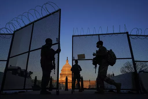 National Guard soldiers open a gate of the razor wire-topped perimeter fence around the Capitol to allow a colleague in at sunrise in Washington, March 8, 2021. (AP Photo/Carolyn Kaster, File)