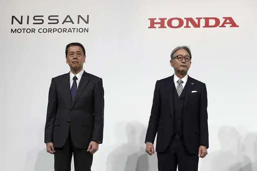 Nissan Chief Executive Makoto Uchida, left, Honda Chief Executive Toshihiro Mibe, right, with Takao Kato, CEO of Mitsubishi Motors, not in photo, pose for photographers during a joint news conference in Tokyo, Japan, on Dec. 23, 2024. (AP Photo/Eugene Hoshiko, File)