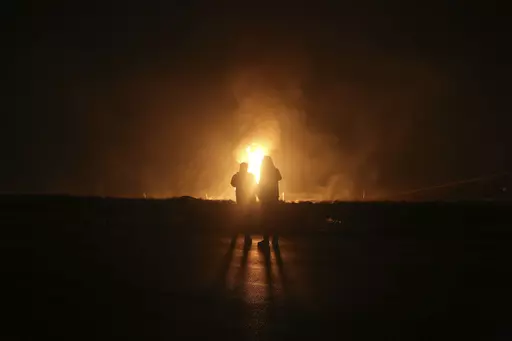 Two men look at flames after a natural gas pipeline explodes outside the city of Boroujen in the western Chaharmahal and Bakhtiari province, Iran, in early Wednesday, Feb. 14, 2024. Explosions struck a natural gas pipeline in Iran early Wednesday, with an official blaming the blasts on a "sabotage and terrorist action" in the country as tensions remain high in the Middle East amid Israel's war on Hamas in the Gaza Strip. (Reza Kamali Dehkordi/Fars News Agency via AP)