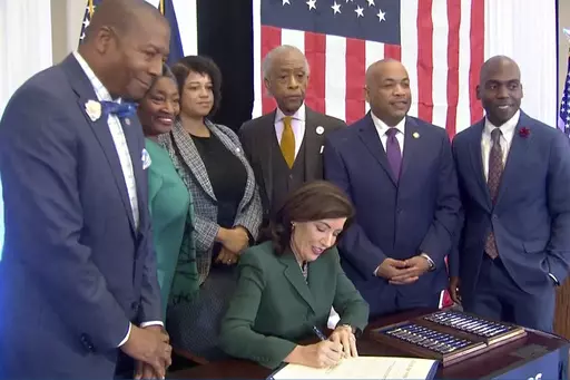 CORRECTS CITY TO NEW YORK - This image from video provided by the Office of The Governor shows New York Gov. Kathy Hochul signing a bill in New York, Tuesday, Dec. 19, 2023, to create a commission tasked with considering reparations to address the persistent, harmful effects of slavery in the state. She is joined by, standing from left: Dr. Yohuru Williams, Founding Director of the Racial Justice Initiative at the University of St. Thomas; Andrea Stewart-Cousins, Majority Leader of the NY State 