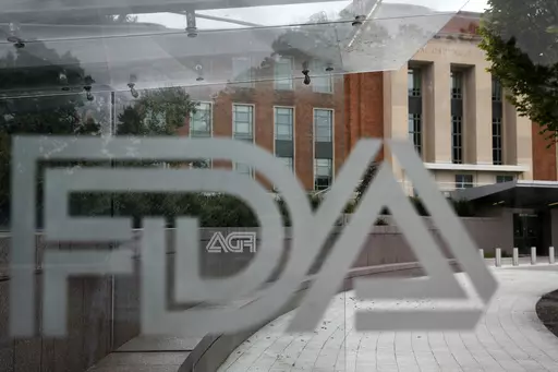 A U.S. Food and Drug Administration building is seen behind FDA logos at a bus stop on the agency's campus in Silver Spring, Md., on Aug. 2, 2018. Federal health advisers voted against an experimental treatment for Lou Gehrig’s disease at a Wednesday, Sept. 27, 2023, meeting prompted by years of patient efforts seeking access to the unproven therapy. (AP Photo/Jacquelyn Martin, File)