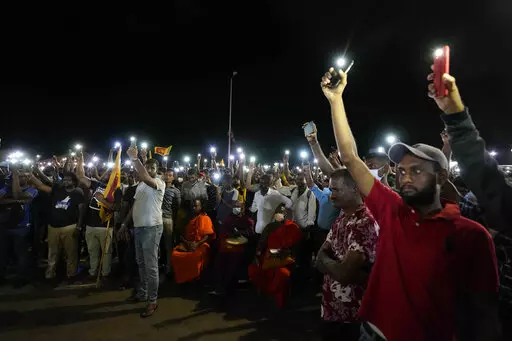 Sri Lankans hold up their mobile phone torches during a vigil condemning police shooting at protesters in Rambukkana, 90 kilometers (55 miles) northeast of Colombo, at a protest outside the president's office in Colombo, Sri Lanka, Tuesday, April 19, 2022. Sri Lankan police opened fire Tuesday at a group of people protesting new fuel price increases, killing one and injuring 10 others, in the first shooting by security forces during weeks of demonstrations over the country's worst economic crisi