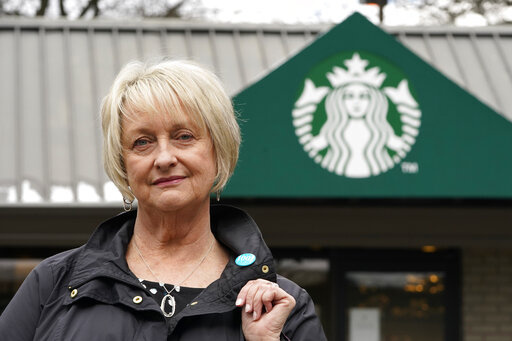 Pam Blauman-Schmitz, who was a union rep at Starbucks in the mid-1980's, poses for a photo in front of a Starbucks coffee shop Tuesday, Feb. 22, 2022, in Seattle. Starbucks, now facing union elections at more than 100 U.S. stores, has spent decades fighting unionization. (AP Photo/Elaine Thompson)