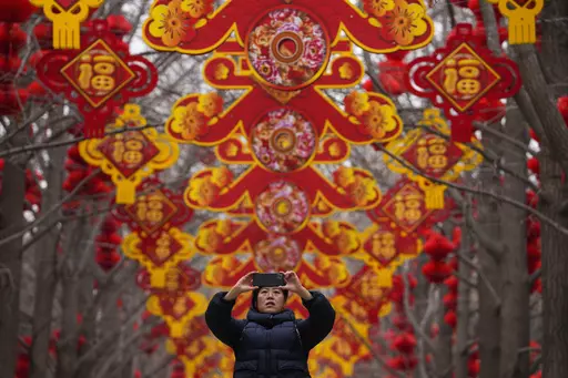 A woman takes a picture of red lanterns and decorations on display along the trees ahead of the Chinese Lunar New Year at Ditan Park in Beijing, Feb. 4, 2024. In many Asian cultures, the Lunar New Year is a celebration marking the arrival of spring and the start of a new year on the lunisolar calendar. It's the most important holiday in China where it's observed as the Spring Festival. (AP Photo/Andy Wong, file)