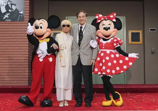 Mickey Mouse, from left, Elizabeth Gluck, Richard M. Sherman and Minnie Mouse pose for a photo at the ceremony honoring the Sherman Brothers with the rename of Disney Studios Soundstage A at the world premiere of Disney's "Christopher Robin" at the Walt Disney Studios, July 30, 2018, in Burbank, Calif. Sherman, one half of the prolific, award-winning pair of brothers who helped form millions of childhoods by penning classic Disney tunes, died Saturday, May 25, 2024. He was 95. (Photo by Willy Sa