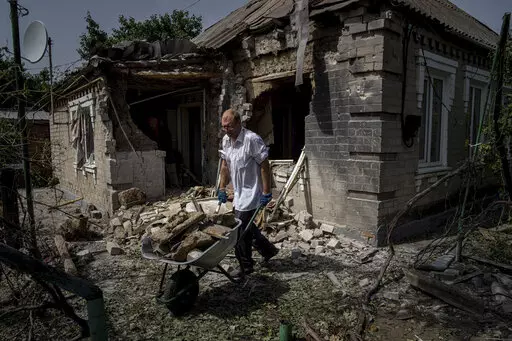 Dmyto Shengur cleans rubble in front of the house which was damaged after Russian bombardment of residential area in Nikopol, Ukraine, on Monday, Aug, 22, 2022. In Nikopol, across the river from Ukraine's main nuclear power plant, Russian shelling wounded four people Monday, an official said. The city on the Dnipro River has faced relentless pounding since July 12 that has damaged some 850 buildings and sent about half its population of 100,000 fleeing. (AP Photo/Evgeniy Maloletka)