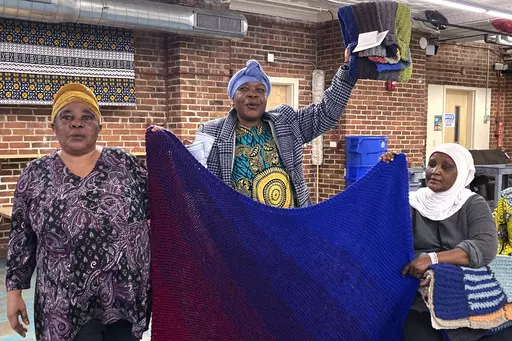 Mochozi Bigelegele, left, and Martha Mlebinge, center, both originally from Congo, and Fatuma Hussein, right, originally from Burundi, hold handmade blankets they picked out at a Welcome Blanket giveaway event on March 21, 2023, in Burlington, Vt. The blankets were made by Vermont and out-of-state crafters as gifts for refugees to welcome them to the community as part of the national Welcome Blanket project. (AP Photo/Lisa Rathke)