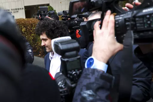 FTX founder Sam Bankman-Fried, center, is escorted to his car from the U.S. District Court in Manhattan, Thursday, Dec. 22, 2022, in New York. A judge agreed to a request by prosecutors to keep it secret that two of Bankman-Fried's executive associates had turned against him so that the cryptocurrency entrepreneur would agree not to fight extradition from the Bahamas to the United States, according to transcripts of plea deals made public Friday, Dec. 23, 2022. (AP Photo/Julia Nikhinson)