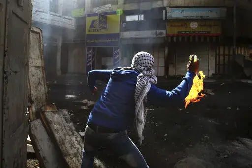 A Palestinian protester throws a Molotov cocktail towards Israeli soldiers during clashes in the West Bank city of Hebron, April 3, 2013. On social media, the world has cheered Ukrainians as they stockpile Molotov cocktails and take up arms against an occupying army. When Palestinians and Iraqis do the same thing, they are branded terrorists and legitimate targets. (AP Photo/Nasser Shiyoukhi, File)