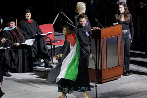 A graduate twirls with her Palestinian flag cape during the Emerson College commencement ceremony at Boston University's Agganis Arena, Sunday, May 12, 2024, in Boston. Many students verbally protested throughout the ceremony. (Pat Greenhouse/The Boston Globe via AP)