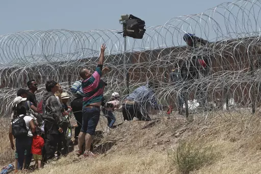 Migrants cross a barbed-wire barrier at the US-Mexico border, as seen from Ciudad Juarez, Mexico, Thursday, May 11, 2023. Migrants rushed across the Mexico border in hopes of entering the U.S. in the final hours before pandemic-related asylum restrictions are lifted. (AP Photo/Christian Chavez, File)