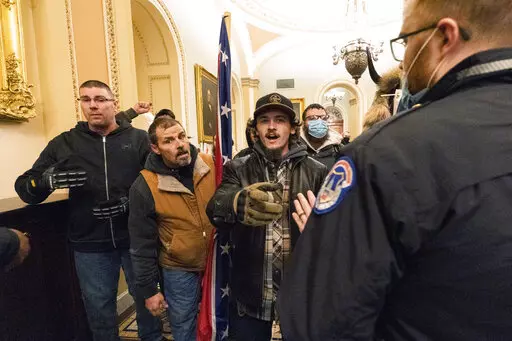 Kevin Seefried, second from left, holds a Confederate battle flag as he and other insurrectionists loyal to President Donald Trump are confronted by U.S. Capitol Police officers outside the Senate Chamber inside the Capitol in Washington, Jan. 6, 2021. A federal judge on Wednesday, June 15, 2022, convicted Kevin Seefried and his adult son Hunter Seefried of charges that they stormed the U.S. Capitol together to obstruct Congress from certifying President Joe Biden’s 2020 electoral victory. (A