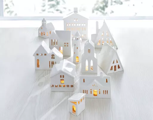 This image provided by Crate & Barrel shows their collection of white ceramic buildings. Crate & Barrel's collection includes alpine homes and hotels as well as midcentury split levels and ranch homes. Add a tealight for a welcoming glow. (Crate & Barrel via AP)