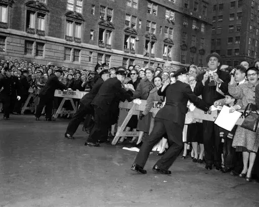New York City policemen push against police stanchions at Park Avenue and 50th street, New York on Oct. 21, 1957 in effort to contain crowd attempting to view Queen Elizabeth II as she drove to the hotel Waldorf-Astoria. (AP Photo)