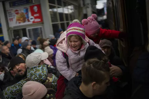 People holding their children struggle to get on a train to Lviv at the Kyiv station, Ukraine, Monday, March 7, 2022. Russia announced yet another cease-fire and a handful of humanitarian corridors to allow civilians to flee Ukraine. Previous such measures have fallen apart and Moscow's armed forces continued to pummel some Ukrainian cities with rockets Monday. (AP Photo/Emilio Morenatti)
