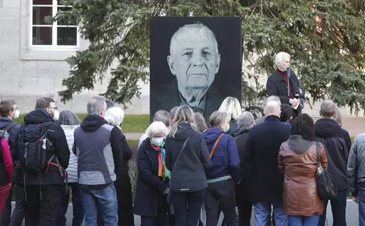 Participants of a memorial service for Buchenwald survivor Boris Romantschenko stand in front of his photo in Weimar, Germany Tuesday, March 22, 2022. Germany’s parliament has paid tribute to Boris Romanchenko, who survived several Nazi concentration camps during World War II but was killed last week during an attack in the Ukrainian city of Kharkiv. He was 96. (Bodo Schackow/dpa via AP)