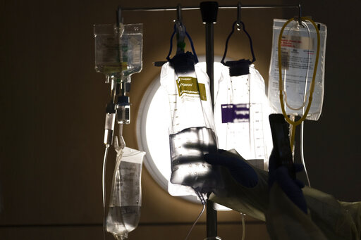Nurse manager Edgar Ramirez checks on IV fluids while talking to a COVID-19 patient at Providence Holy Cross Medical Center in Los Angeles, Dec. 13, 2021. Some conservatives are taking aim at policies that allow doctors to consider race as a risk factor when allocating scarce COVID-19 treatments, saying the protocols discriminate against white people. Medical experts say the opposition is misleading. (AP Photo/Jae C. Hong, File)