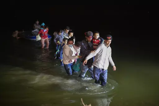 Migrant families wade through shallow waters toward Roma, Texas, March 24, 2021. A federal judge was poised Friday, Dec.8, 2023, to prohibit separation of families at the border for purposes of deterring immigration for eight years. (AP Photo/Dario Lopez-Mills, File)