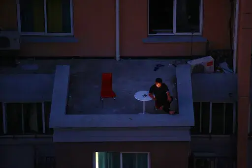 A man looks at his smartphone on a balcony in a residential community in Shanghai, China, Monday, April 11 2022. The U.S. has ordered all non-emergency consular staff to leave Shanghai, which is under a tight lockdown to contain a COVID-19 surge. Many residents in the city of 26 million have been confined to their homes for up to three weeks as China maintains its "zero-COVID" strategy of handling outbreaks with strict isolation and mass testing. (AP Photo)