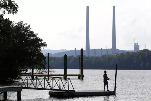 In this Aug. 7, 2019, file photo, a man fishes at William B. Ladd Park near the Kingston Fossil Plant in Kingston, Tenn. The largest public power company in the U.S. is launching a program to develop and fund new small modular nuclear reactors as part of its strategy to dramatically reduce greenhouse gas emissions. The board for the Tennessee Valley Authority on Thursday, Feb. 10, 2022 authorized the program to assess moving forward with new nuclear technology, with up to $200 million to be spen