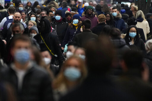 Shoppers walk down Oxford Street, Europe's busiest shopping street, in London, Dec. 23, 2021. The British government confirmed Saturday Feb. 19, 2022, that people with the coronavirus will not be legally required to self-isolate starting next week, as part of a plan for “living with COVID” that is also likely to see testing for the virus scaled back. (AP Photo/Frank Augstein, File)