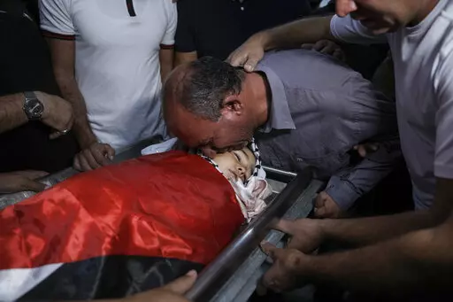 Father of 7-year-old Palestinian boy Rayan Suleiman, kisses his body at a hospital in the West Bank village of Beit Jala just before his funeral Friday, Sept. 30, 2022. The U.S. State Department has called on Israel to open a "thorough" investigation into the mysterious death of the boy, who collapsed and died shortly after Israeli soldiers came to his home in the occupied West Bank. Relatives said he had no previous health problems and accused the army of scaring the child to death. The army ca