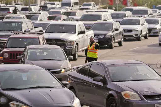 An officer directs traffic at Love Field Airport in Dallas, Wednesday, Dec. 21, 2022. The rate of people working from home dropped from 17.9% in 2021 to 15.2% in 2022, according to new survey data released Thursday, Sept. 14, 2023, by the U.S. Census Bureau on life in America, covering commuting times internet access, family life, income, education levels, disabilities, military service and employment. (AP Photo/LM Otero, File)