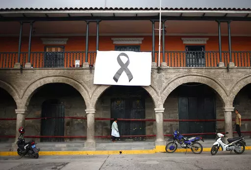 A woman passes below a big black ribbon displayed as a symbol of people who were killed during protests against new President Dina Boluarte, in Ayacucho, Peru, Sunday, Dec. 18, 2022. The eight deaths this week that converted Ayacucho into the epicenter of violence in Peru's still unfolding crisis is for many a stark reminder of the region's bloody past and longstanding neglect by authorities in the far-away capital. (AP Photo/Hugo Curotto)