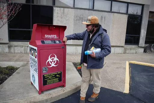 Joe Solomon, Democratic candidate for city council and co-director of the non-profit Solutions Oriented Addiction Response, stops by a syringe disposal box outside the Kanawha-Charleston Health Department, Tuesday, April 5, 2022, in Charleston, W.Va. Solomon had spent three days eating at soup kitchens and sleeping under bridges and in parking lots while interviewing residents about the changes they’d like to see in the city’s response to issues like homelessness and substance use. (AP Photo