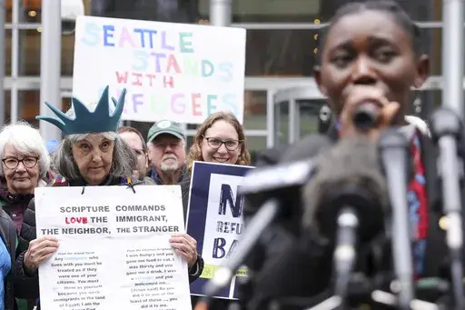 Retired reverend Carrol Jensen wears a hat mimicking the Statue of Liberty as Reverend Emilie Binja, a former refugee from the Democratic Republic of Congo speaks during a rally outside the U.S District Court after a federal judge blocked President Donald Trump's effort to halt the nation's refugee admissions system, Tuesday, Feb. 25, 2025 in Seattle. (AP Photo/Ryan Sun)