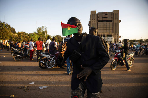 A Save Burkina Faso movement supporter holds a Burkina Faso flag after it was announced that Lt. Col. Paul Henri Sandaogo Damiba has taken the reins of the country in Ouagadougou Monday Jan. 24, 2022. More than a dozen mutinous soldiers declared Monday on state television that a military junta now controls Burkina Faso after they detained the democratically elected president following a day of gun battles in the capital. (AP Photo/Sophie Garcia)